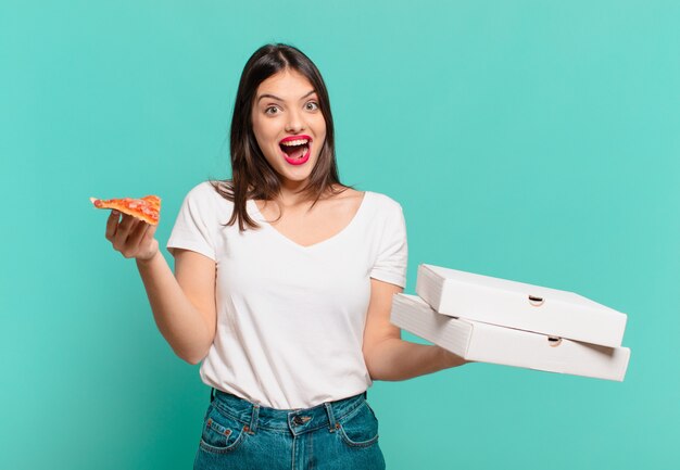 jeune jolie femme surprise expression et tenant une pizza