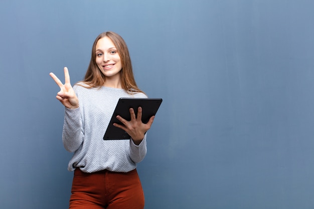 Jeune Jolie Femme Avec Une Tablette Contre Un Mur Bleu Avec Une Surface