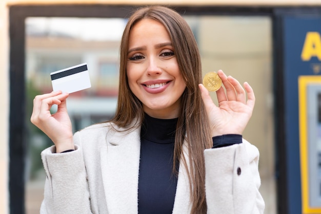 Jeune jolie femme tenant un Bitcoin à l'extérieur