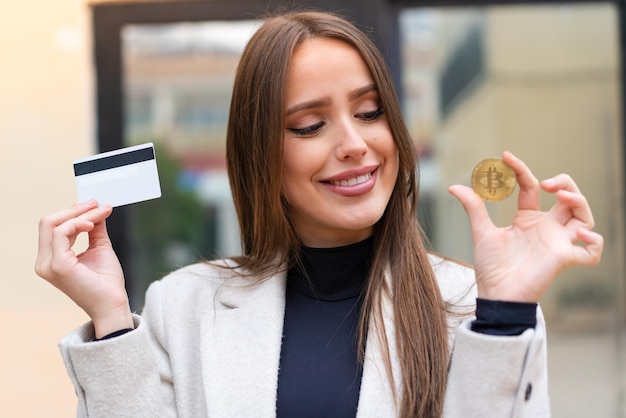 Jeune jolie femme tenant un Bitcoin à l'extérieur