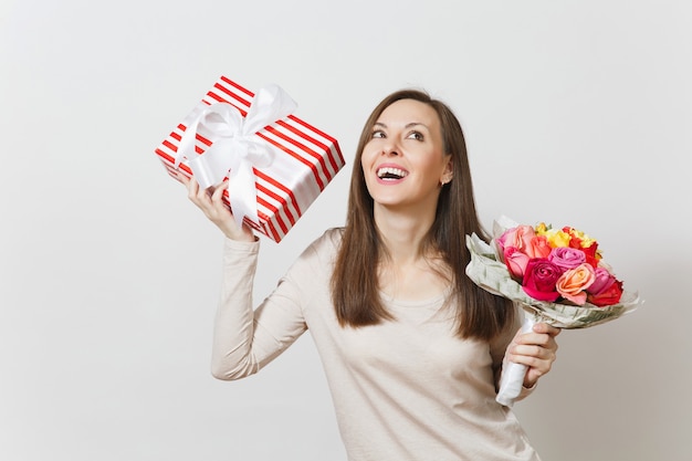 Jeune jolie femme tenant un bouquet de belles fleurs roses, boîte présente avec cadeau isolé sur fond blanc. Copiez l'espace pour la publicité. Concept de la Saint-Valentin ou de la Journée internationale de la femme