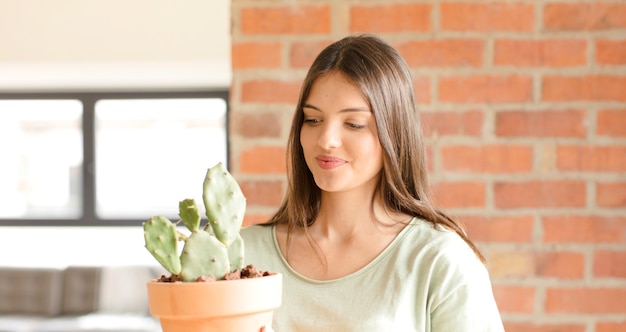 Photo jeune jolie femme tenant un cactus à la maison