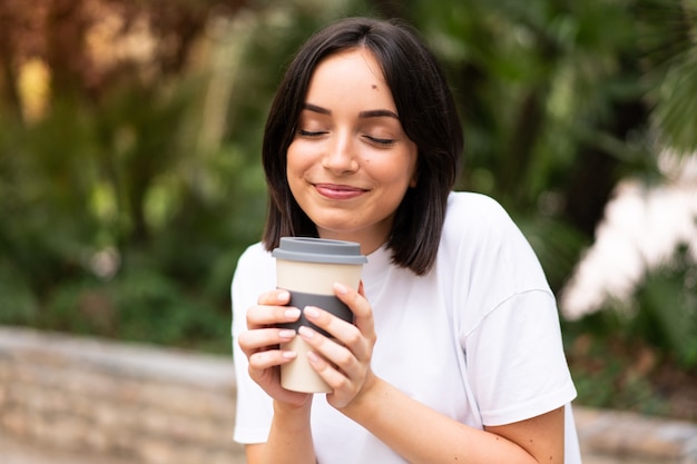 Jeune jolie femme tenant un café à emporter à l'extérieur