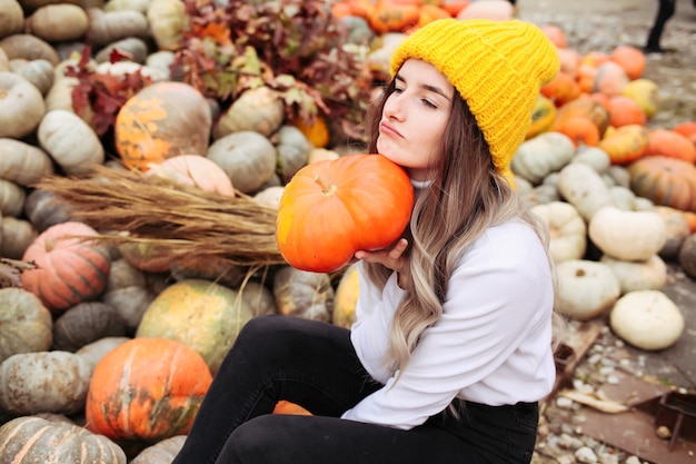 Jeune jolie femme tenant une citrouille d'halloween orange