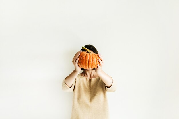 Jeune jolie femme tenant la citrouille d'halloween sur une surface blanche