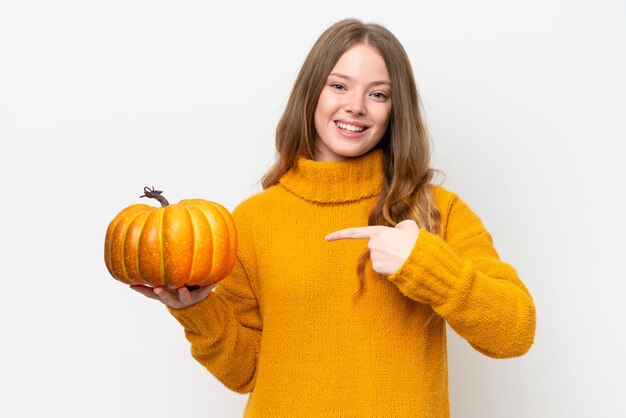 Jeune jolie femme tenant une citrouille isolée sur fond blanc et la pointant