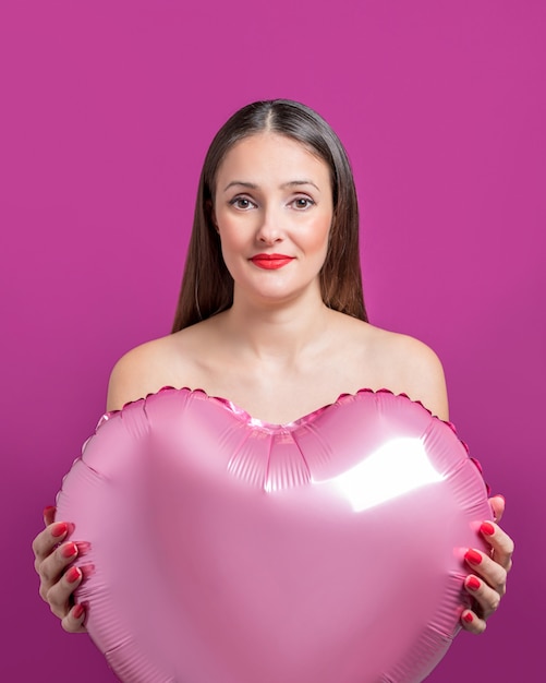 Jeune jolie femme tenant une montgolfière en forme de coeur