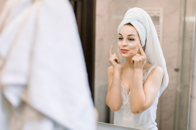 Jeune jolie femme avec la tête enveloppée dans une serviette