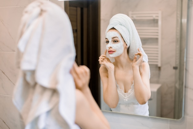 Jeune jolie femme avec la tête enveloppée dans une serviette