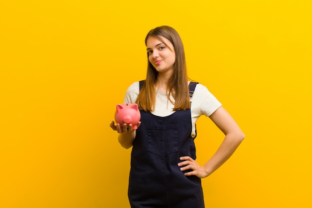 Jeune jolie femme avec une tirelire contre orange