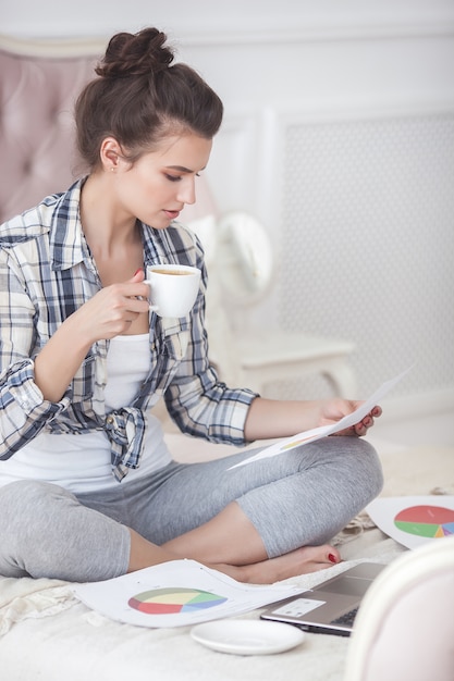 Jeune jolie femme travaillant à la maison à l'ordinateur portable