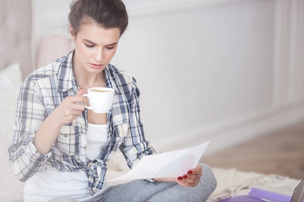 Jeune jolie femme travaillant à la maison sur l'ordinateur portable