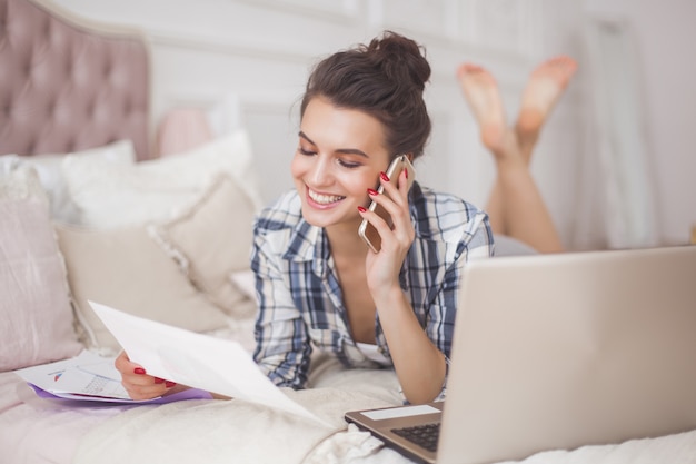 Jeune jolie femme travaillant à la maison à l'ordinateur portable