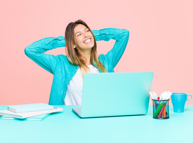 Jeune jolie femme travaillant avec un ordinateur portable souriant et se sentant détendu, satisfait et insouciant, riant positivement et glaçant