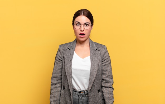 Jeune jolie femme à la très choquée ou surprise, regardant la bouche ouverte en disant wow