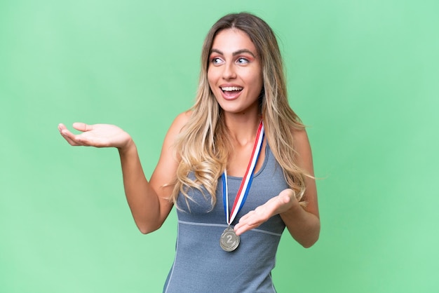 Jeune jolie femme uruguayenne sportive avec des médailles sur fond isolé avec une expression faciale surprise