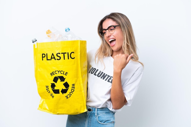 Jeune jolie femme uruguayenne tenant un sac plein de bouteilles en plastique à recycler isolé sur fond blanc célébrant une victoire