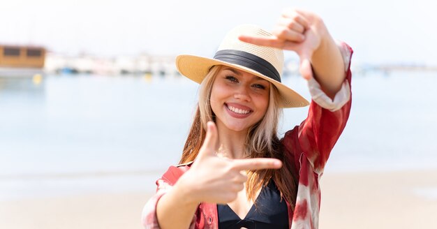 Jeune jolie femme en vacances d'été à la plage en se concentrant sur le visage. Symbole d'encadrement