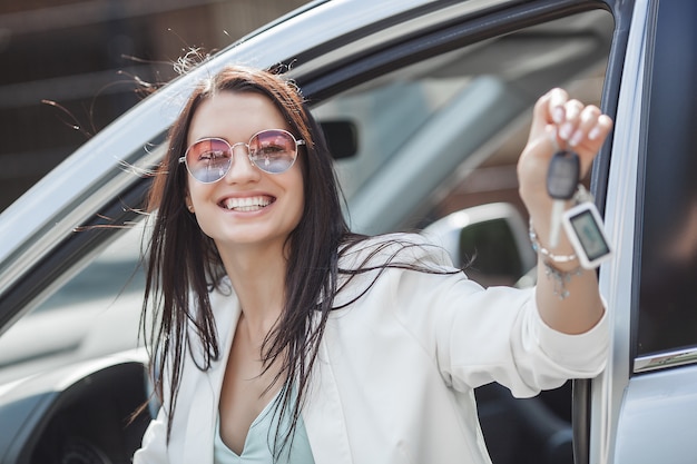 Jeune jolie femme vient d'acheter une nouvelle voiture. femme tenant les clés de la nouvelle automobile.