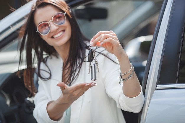 Jeune jolie femme vient d'acheter une nouvelle voiture. femme tenant les clés de la nouvelle automobile.