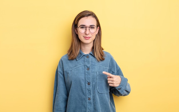 Jeune jolie fille à l'air fière, confiante et heureuse, souriante et se montrant elle-même ou faisant le signe numéro un