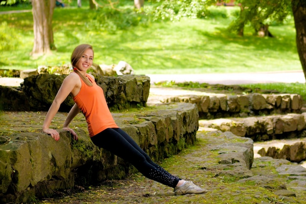 Jeune jolie fille blonde faisant du yoga dans un parc verdoyant et ensoleillé le matin, concept de sport lifestyle.