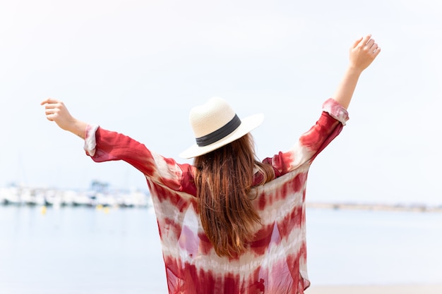 Jeune jolie fille blonde sur la plage en vacances d'été en position arrière