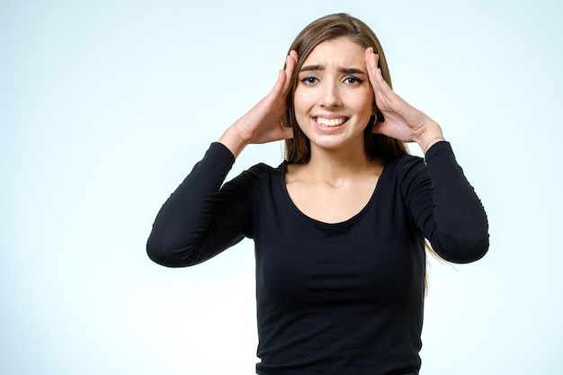 Jeune jolie fille brune touchant sa tête sur fond blanc