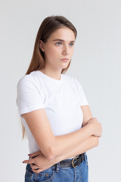 Jeune jolie fille caucasienne aux cheveux longs en t-shirt, jean bleu au studio