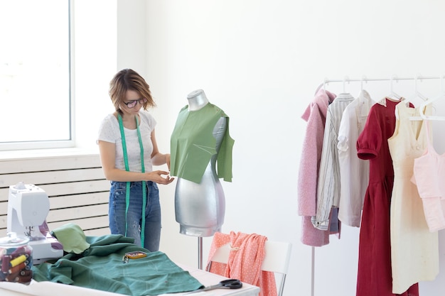 Jeune jolie fille couturière designer avec des lunettes et un ruban à mesurer fait un nouveau produit