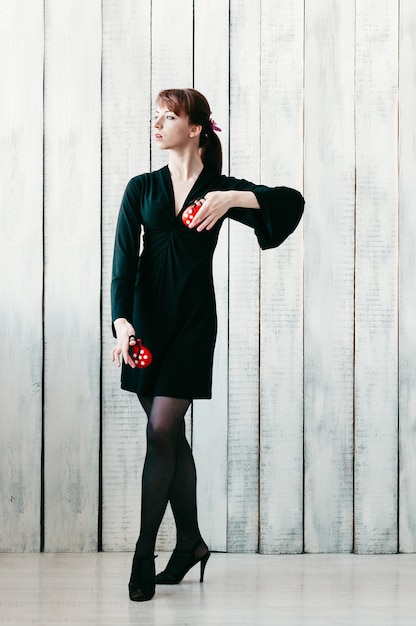 Photo jeune jolie fille dansante en robe noire, avec des castagnettes rouges