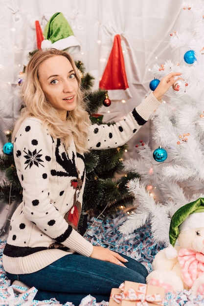 Jeune jolie fille décorant l'arbre de Noël à la maison