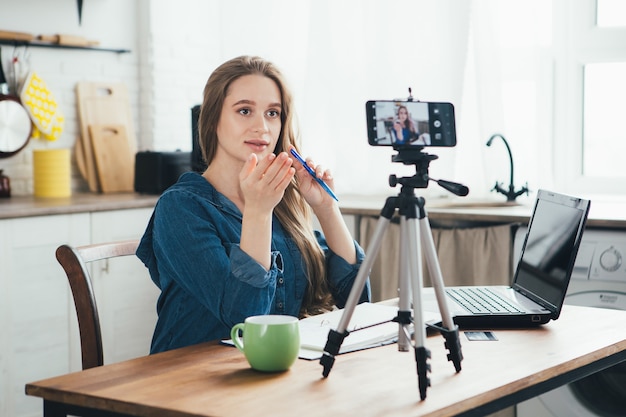 Jeune jolie fille enceinte travaille à la maison en mode auto-isolement en quarantaine et enregistre des vidéos sur son smartphone