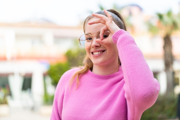 Jeune jolie fille à l'extérieur avec des lunettes avec une expression heureuse