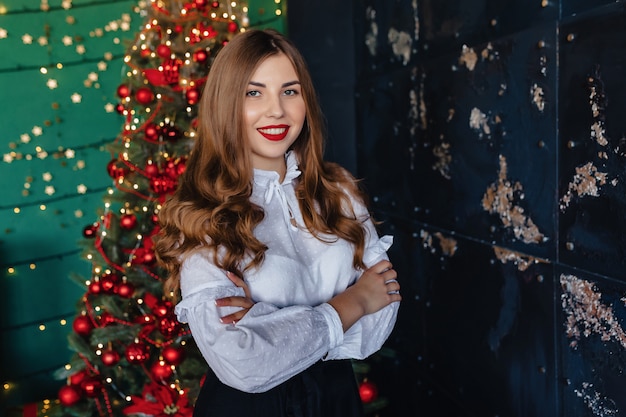 Jeune jolie fille en habits de fête sur le fond d&#39;un sapin de Noël