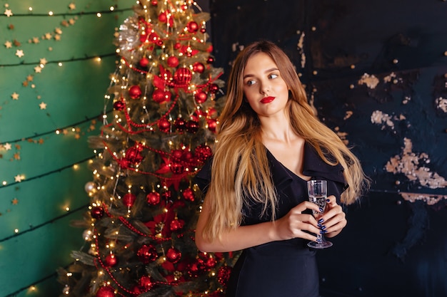 Jeune jolie fille en habits de fête sur le fond d&#39;un sapin de Noël