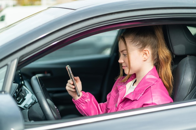 Jeune jolie fille à l'intérieur d'une voiture utilisant le téléphone portable