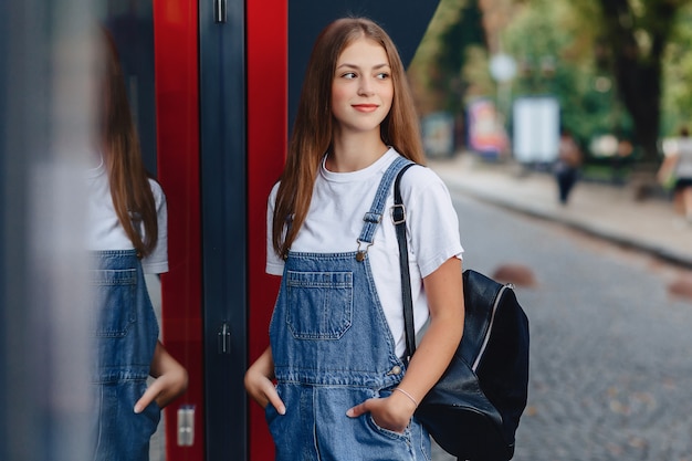 Jeune jolie fille avec mallette marche sur les reflets urbains de la rue