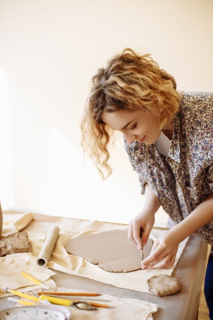 Photo jeune jolie fille prépare de l'argile pour faire de la poterie dans son atelier