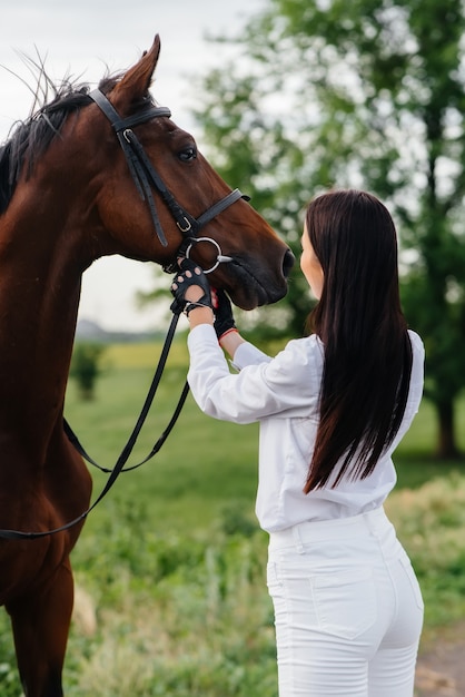 Une jeune jolie fille rider pose près d'un étalon pur-sang dans un ranch