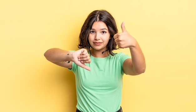 Jeune jolie fille se sentant confuse, désemparée et incertaine, pondérant le bien et le mal dans différentes options ou choix