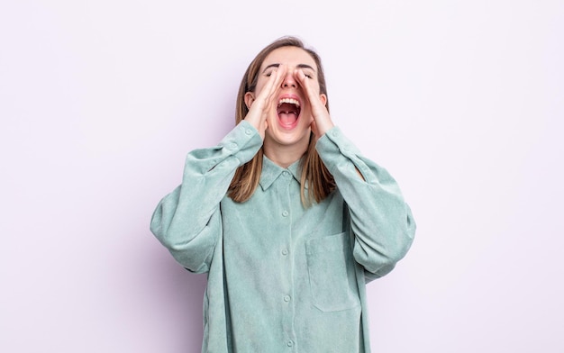 Jeune jolie fille se sentant heureuse, excitée et positive, donnant un grand cri avec les mains à côté de la bouche, appelant