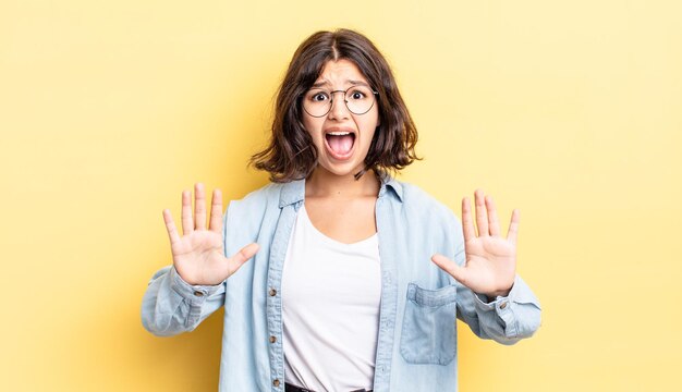 Jeune jolie fille se sentant stupéfaite et effrayée, craignant quelque chose d'effrayant, les mains ouvertes devant lui disant de rester à l'écart