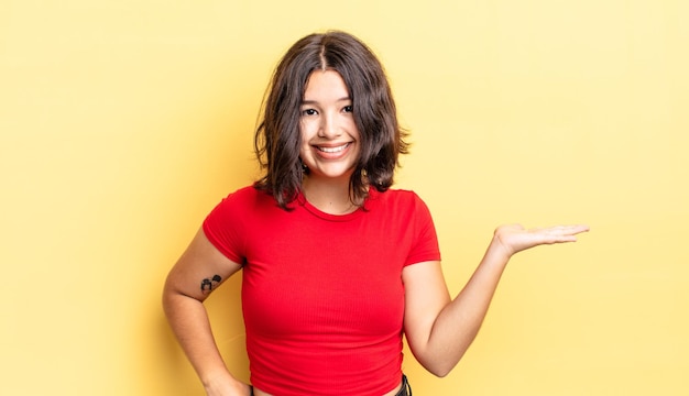 Jeune jolie fille souriante, confiante, réussie et heureuse, montrant un concept ou une idée sur l'espace de copie sur le côté