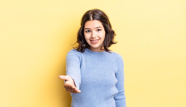 Jeune jolie fille souriante à la recherche de confiance confiante et amicale offrant une poignée de main pour conclure un accord de coopération