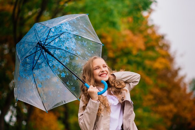 Jeune jolie fille souriante sous parapluie dans une forêt d'automne