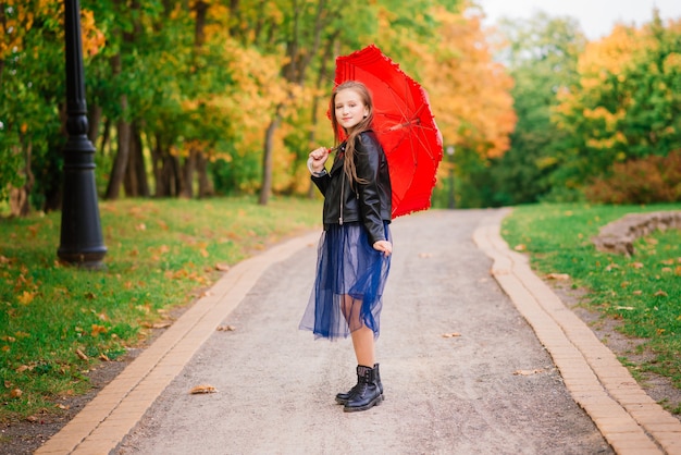 Jeune jolie fille souriante sous parapluie dans une forêt d'automne