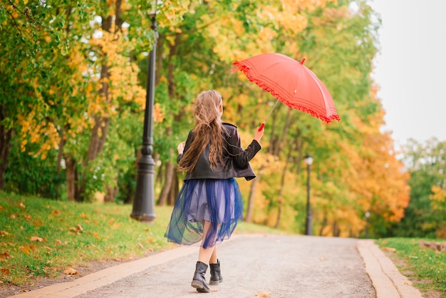 Jeune jolie fille souriante sous parapluie dans une forêt d'automne