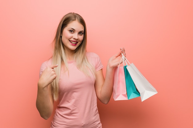 Jeune jolie fille surprise, se sent réussie et prospère. Elle tient un sac à provisions.