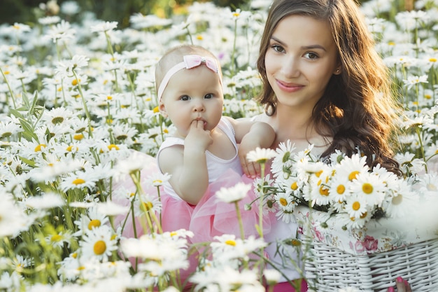 Jeune jolie mère avec son petit bébé à l'extérieur. Belle femme avec sa fille sur la nature. enfant en bas âge avec ses parents sur le champ de camomille